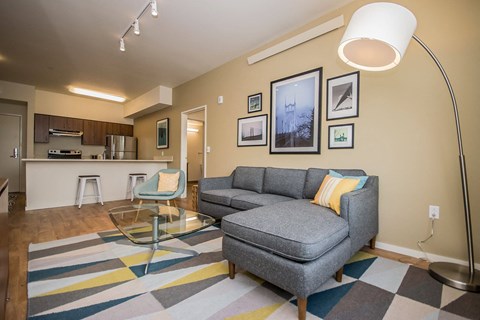 A living room with a grey couch and a glass coffee table.