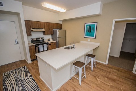 A kitchen with a white counter and bar stools.
