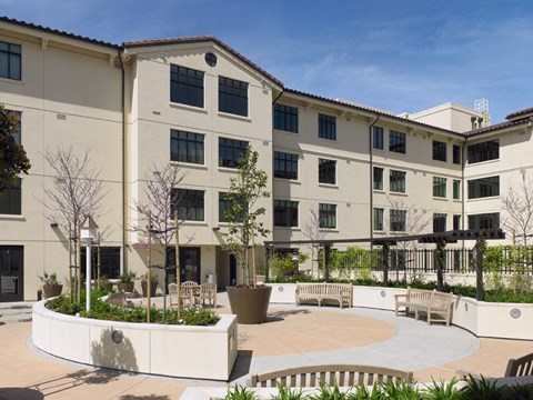 A courtyard with benches and a fence in front of a building.