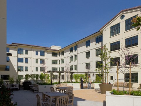 A courtyard with tables and chairs surrounded by buildings.