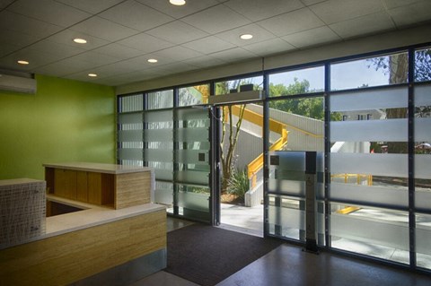 A reception area with a green wall and a glass door.