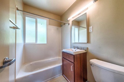 A bathroom with a tub, sink, and mirror.