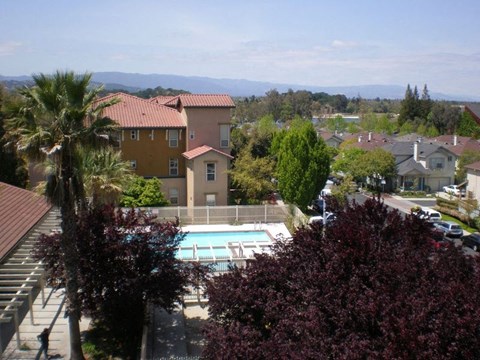 A view of a pool and houses from a balcony.