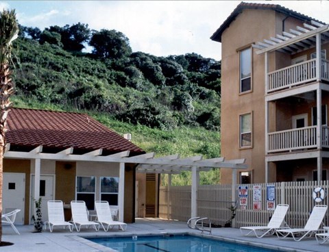 A pool area with a building and chairs.