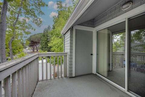 A balcony with a glass door leading to a deck.