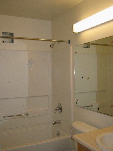 A white bathroom with a toilet, sink, and shower.