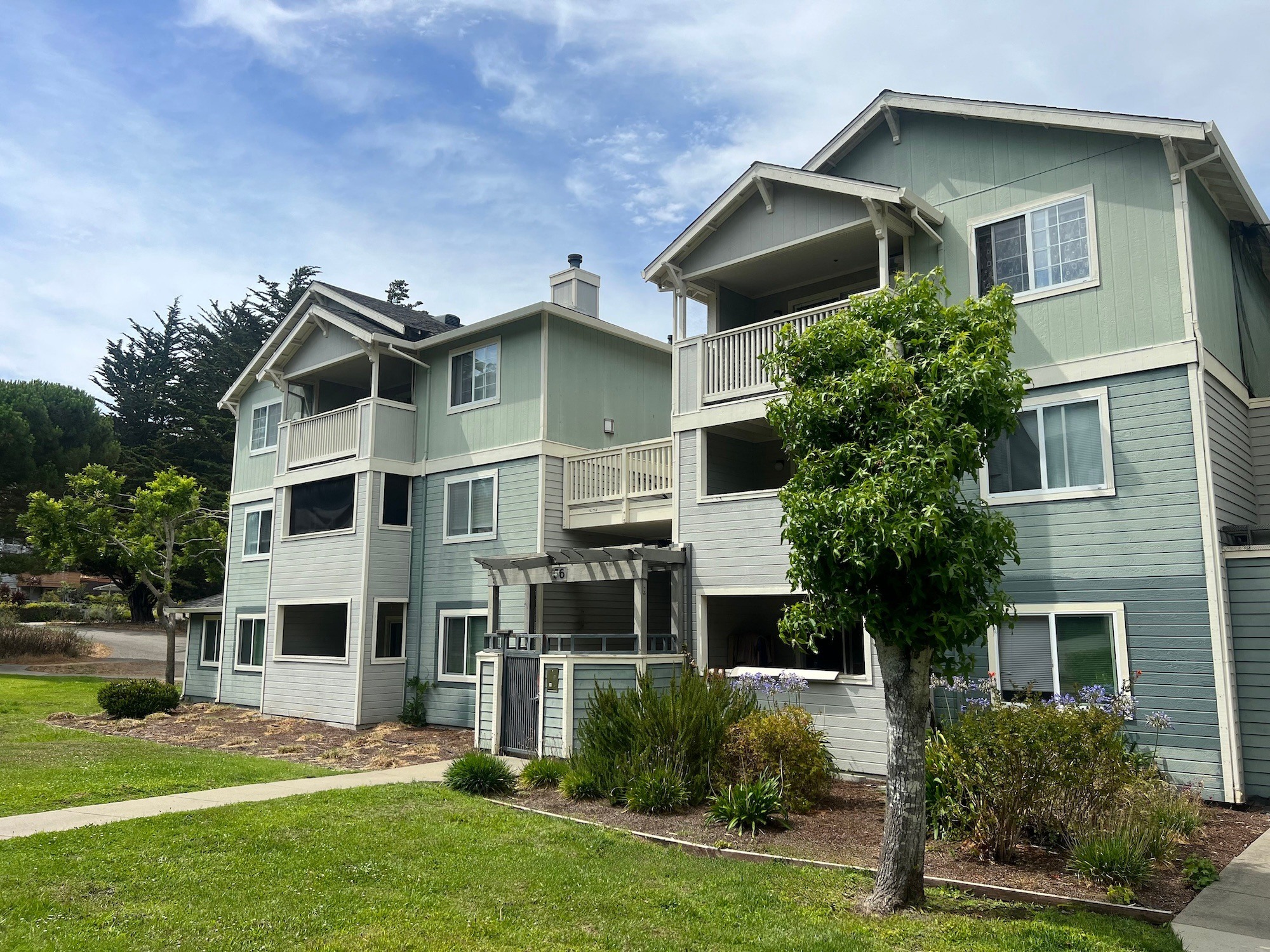 A large house with a balcony and a tree in front.