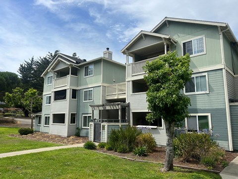 A large house with a balcony and a tree in front.