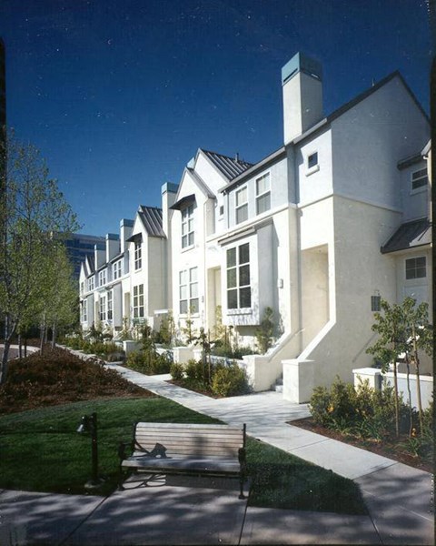 A white building with a black roof and a tree in front of it.