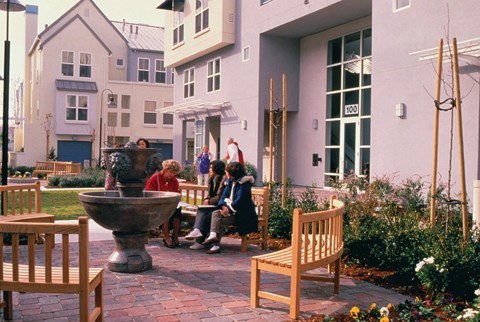 A group of people sitting around a fountain in a courtyard.