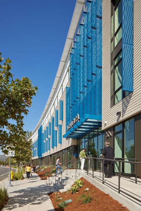 A modern building with a blue glass facade and people walking on the sidewalk.