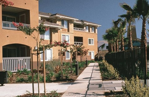 A row of apartment buildings with a sidewalk in front.