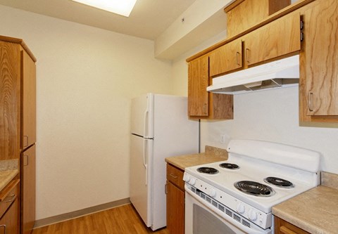 A kitchen with a white stove and refrigerator.