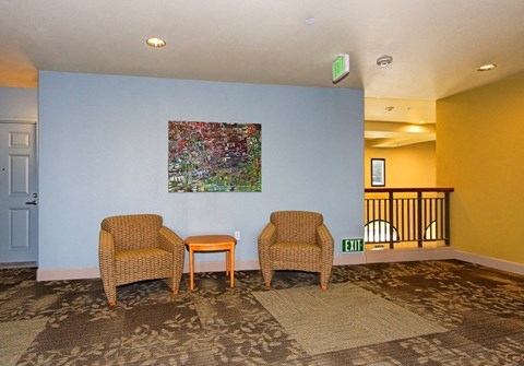 Two chairs and a table are in a room with a painting on the wall.