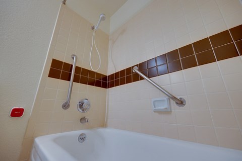 A white bathtub with a shower head and hand held shower.