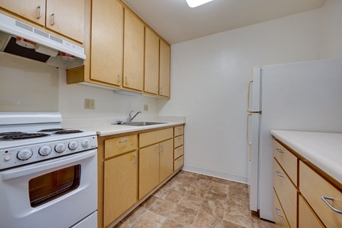 A kitchen with a white stove and wooden cabinets.