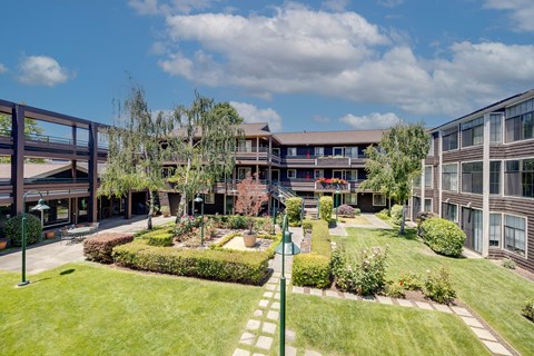 A large grassy area in front of a building with a small garden.