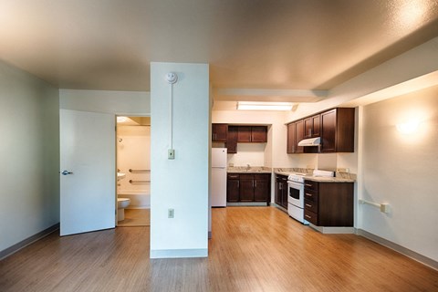 A kitchen with white appliances and wooden floors.