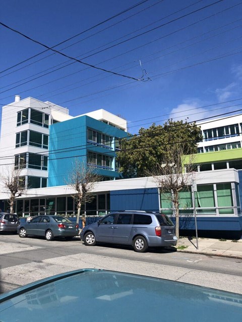 A blue and white building with cars parked in front.