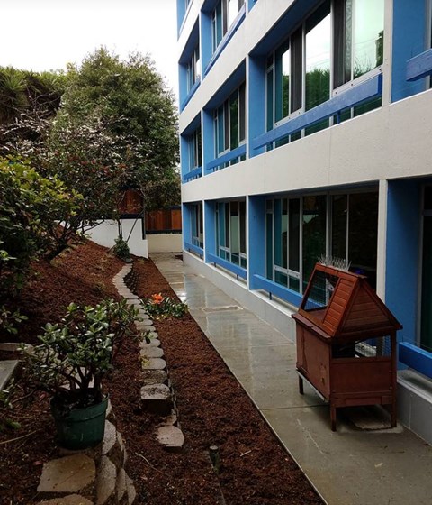 A small wooden structure sits on a patio next to a building.