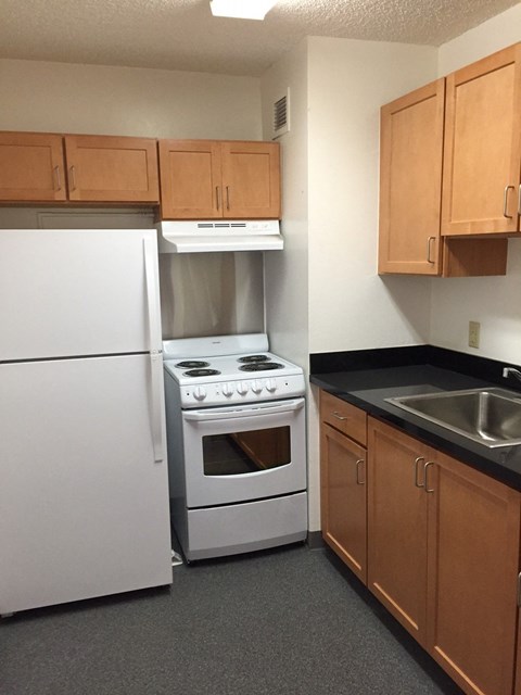A kitchen with a white refrigerator, a white stove, and brown cabinets.