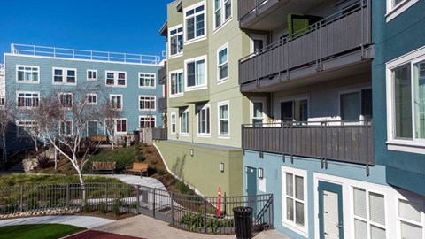 A view of a green and blue building with a tree in front.