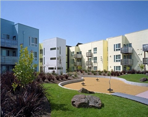 A playground area in front of a row of modern buildings.