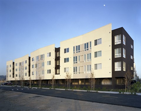 A modern apartment building with a parking lot in front.