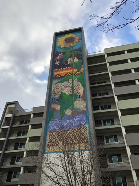 A large mural on a building with a sunflower at the top.