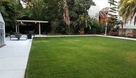 A backyard with a green lawn and a white patio.