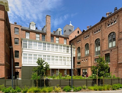 A large building with a white section in the middle is surrounded by smaller buildings.