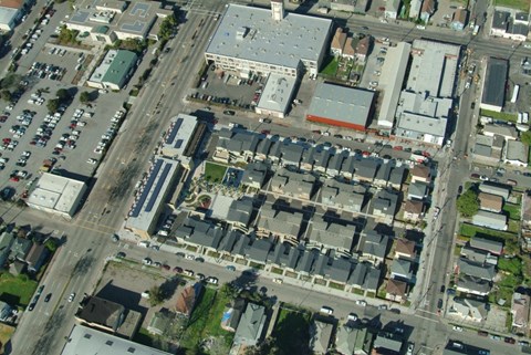 A bird's eye view of a city street with buildings, cars, and trees.