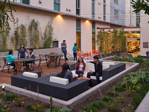 People are sitting and standing on a patio.