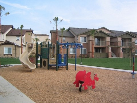 A playground with a red dinosaur toy in the foreground.