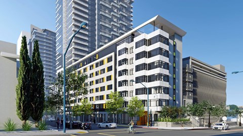 A modern building with a glass facade is surrounded by other tall buildings.