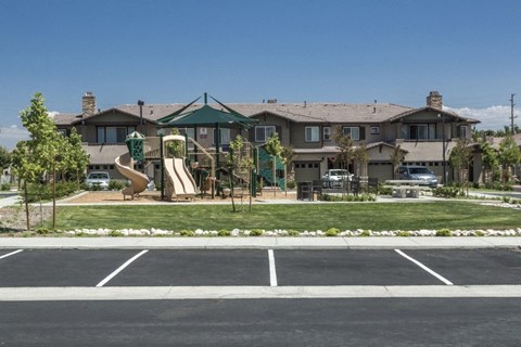 A playground with a slide in front of a house.