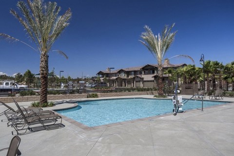 A pool surrounded by palm trees and lounge chairs.