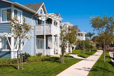 A row of houses with a sidewalk in front.