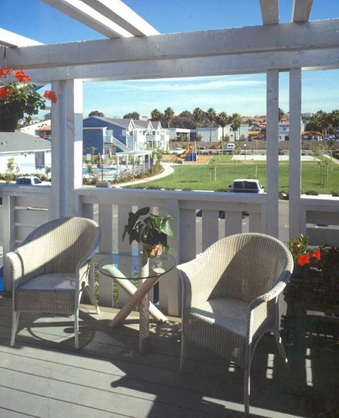 Two chairs and a table on a porch with a view of the street.