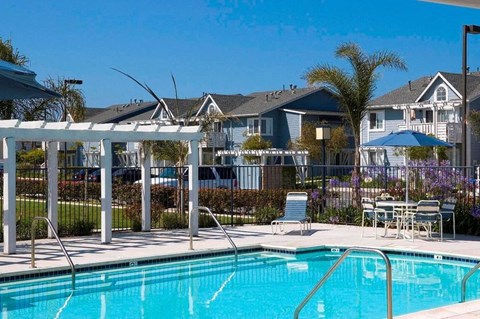 A pool surrounded by chairs and a fence.