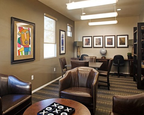 A room with brown leather chairs and a framed painting on the wall.