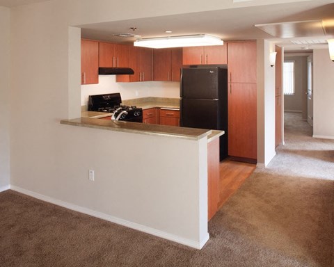 A kitchen with brown cabinets and a black fridge.