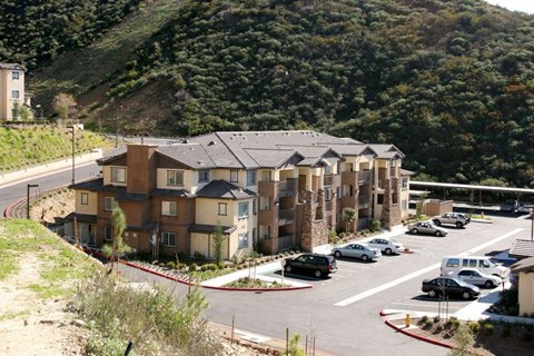 Apartment complex with a parking lot in front.