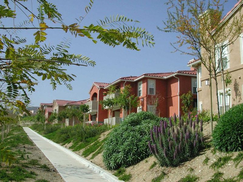 A row of houses with a sidewalk in front of them.