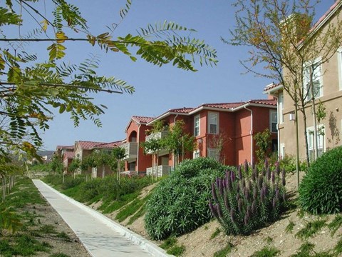 A row of houses with a sidewalk in front of them.