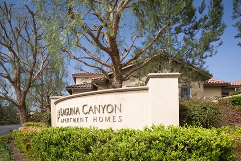 A sign for Augusta Canyon Apartment Homes is in front of a house.