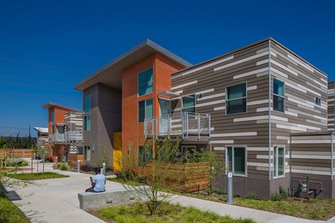 A man is sitting on a concrete platform in front of a modern building.