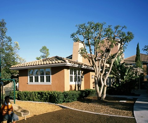 A house with a tan roof and a tree in front of it.