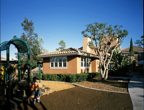 A child is sitting on a swing set in a backyard.