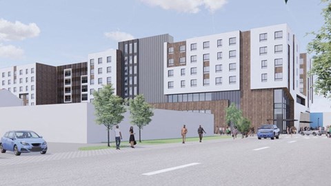 A street view of a modern building with cars and pedestrians.